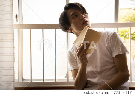 A man reading in a room 77364117