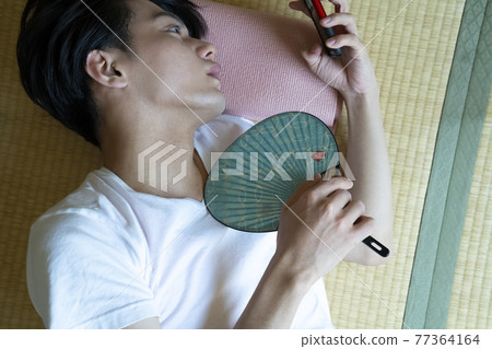 A man looking at a smartphone in the room on a hot day A man looking at a smartphone in the room on a hot day 77364164