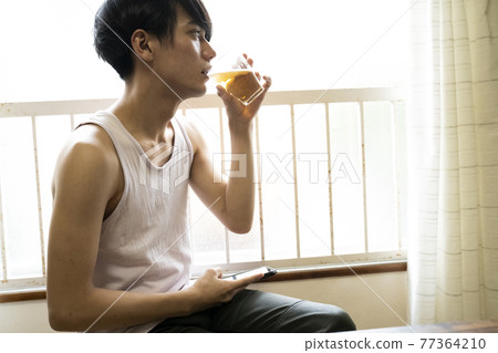 Man drinking a drink in the room 77364210