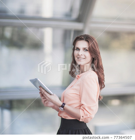 successful business woman with digital tablet standing in the lobby of a modern office successful business woman with digital tablet standing in the lobby of a modern office 77364507
