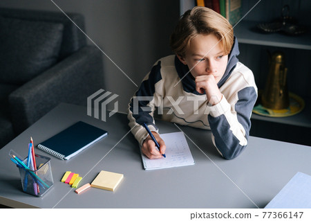 Close-up hands of pupil boy writing in notebook solving math equations sitting at desk at home. Close-up hands of pupil boy writing in notebook solving math equations sitting at desk at home. 77366147