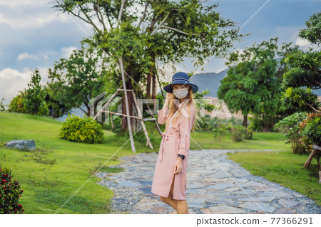 Woman traveler in medical mask looking at the Japanese traditional building. Tourists travel in Japan after the coronavirus epidemic 77366291