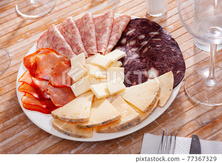 Slicing of smoked sausage, ham, dried pork carbonade and cheese Slicing of smoked sausage, ham, dried pork carbonade and cheese 77367329