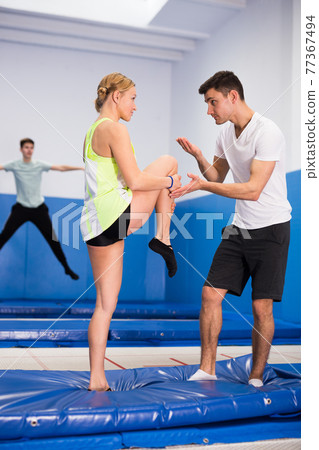 Instructor holding training with woman in trampoline room 77367494