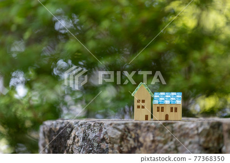 有兩個小的逗人喜愛的玻璃馬賽克屋頂的木房子在新鮮的綠色背景 77368350