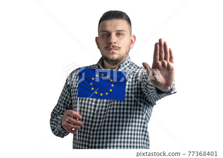 White guy holding a flag of European Union and with a serious face shows a hand stop sign isolated on a white background White guy holding a flag of European Union and with a serious face shows a hand stop sign isolated on a white background 77368401