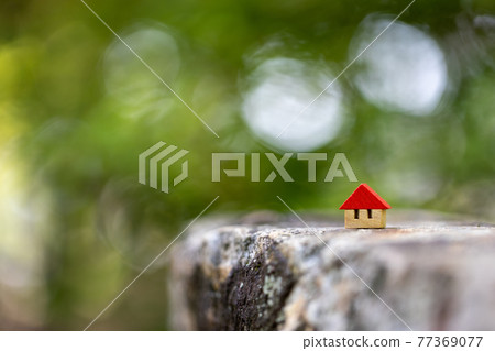 A small cute wooden house with a red roof on a fresh green background A small cute wooden house with a red roof on a fresh green background 77369077