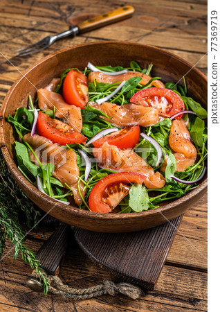 Vegetable salad with smoked salmon, arugula, tomato and green vegetables. wooden background. Top View 77369719