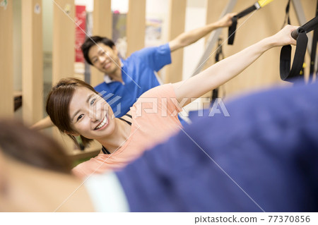 與懸浮訓練器一起鍛煉的年輕男女 與懸浮訓練器一起鍛煉的年輕男女 77370856