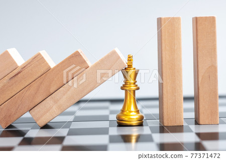 wooden Blocks or Dominoes falling to golden Chess King figure. Business, Risk Management, Solution, economic regression, Insurance 77371472