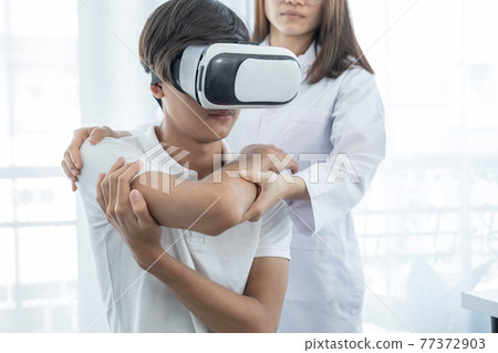 VR box with patient male, Female doctor doing physical therapy by extending the hand, the concept of technology helped the feeling as if a doctor came to treat at home 77372903