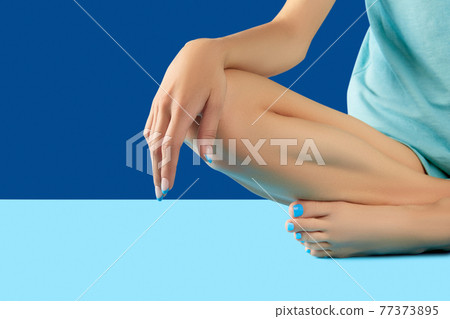 Female legs and hands with fashionable blue nail design 77373895
