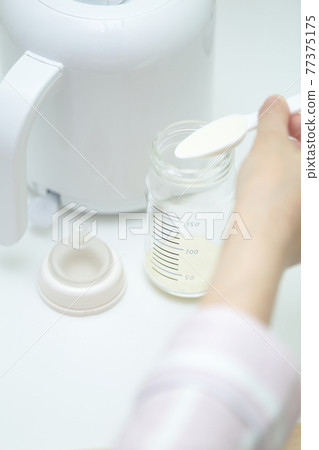 Mom making powdered milk in a baby bottle 77375175
