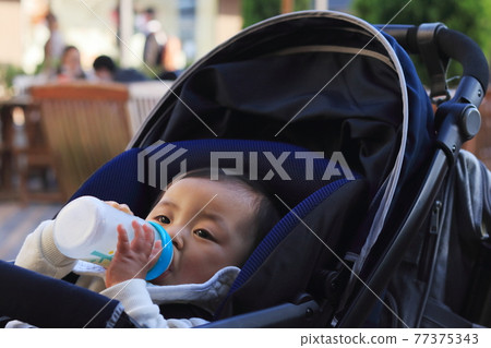 嬰兒車裡喝嬰兒配方奶粉的嬰兒 77375343
