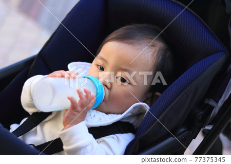 嬰兒車裡喝嬰兒配方奶粉的嬰兒 嬰兒車裡喝嬰兒配方奶粉的嬰兒 77375345
