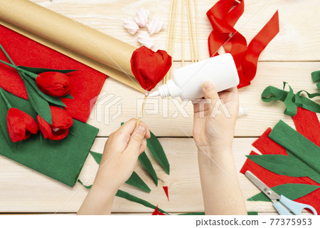 How to make a tulip flower out of paper and marshmallows at home. Marshmallow inside a red tulip bud. Hands make a red tulip. Step-by-step instruction. DIY children's art project 77375953