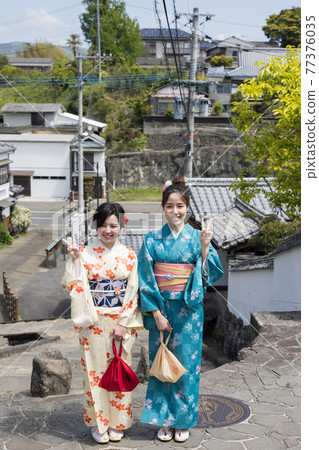 A young woman in a kimono and a friend taking a commemorative photo on the slope of Ameya [Kitsuki City] 77376035