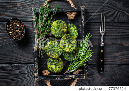 Vegetarian veggie vegetable falafel patty with herbs in a wooden tray. Black background. Top view Vegetarian veggie vegetable falafel patty with herbs in a wooden tray. Black background. Top view 77376324