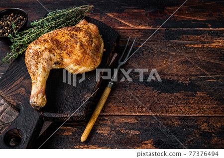 Grilled chicken leg on a wooden board. Dark wooden background. Top view. Copy space Grilled chicken leg on a wooden board. Dark wooden background. Top view. Copy space 77376494