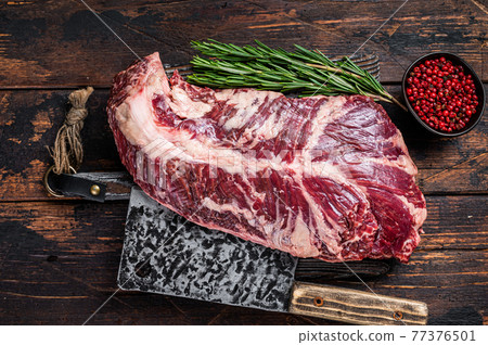 Hanging tender or hanger raw beef meat steak on butcher board with cleaver. Dark wooden background. Top View 77376501