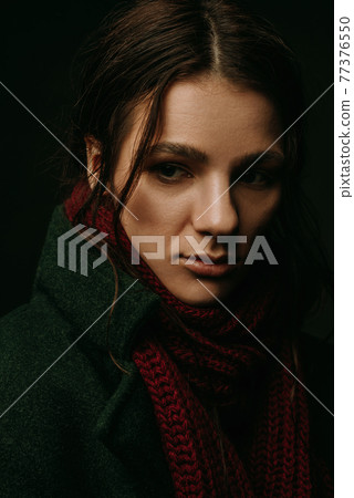 dramatic portrait of a girl in a coat and scarf 77376550