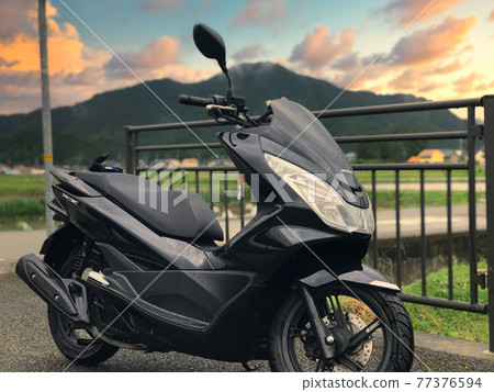 自行車在黃昏時在街上被雨擊中 77376594