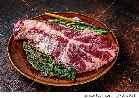 Raw hanging tender or ongle beef meat steak on rustic plate with herbs. Dark background. Top View 77376631