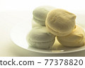 Delicious colored marshmallows on a round white plate is illuminated by the rear window 77378820