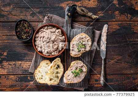 Toasts with Duck pate Rillettes de Canard on wooden board. Dark wooden background. Top View 77379925