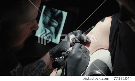Man doing black tattoo of snake in studio Man doing black tattoo of snake in studio 77381044