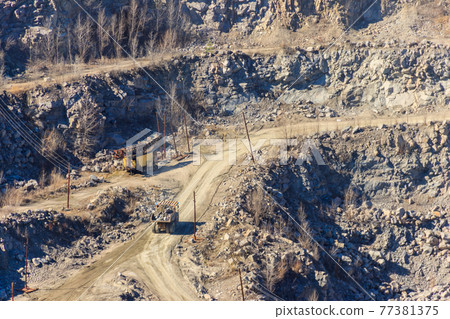Huge granite quarry with working dump trucks and excavators Huge granite quarry with working dump trucks and excavators 77381375