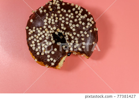 Bitten tasty chocolate donut on a pink background. Top view Bitten tasty chocolate donut on a pink background. Top view 77381427
