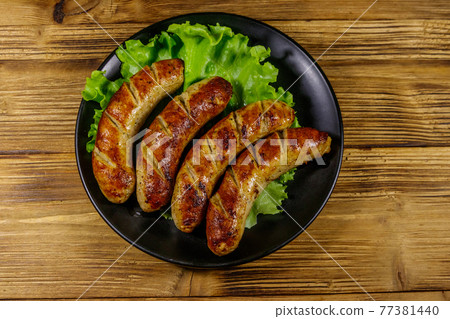 Tasty grilled sausages on a wooden table. Top view 77381440