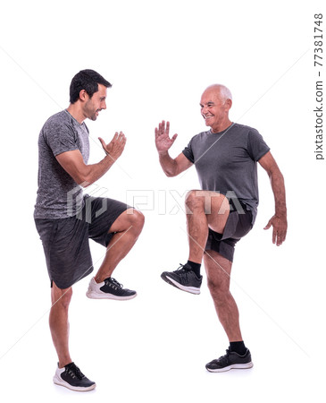 Elderly male client exercising with a fitness trainer, exercise walking in place, steps. On a white isolated background. 77381748