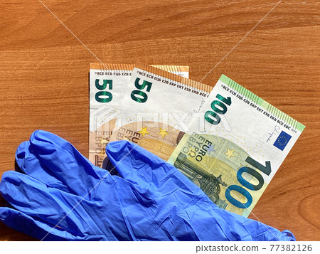 Blue latex gloves and 50 and 100 euro bills. For the cashier or seller, sale. The bottom of the picture Blue latex gloves and 50 and 100 euro bills. For the cashier or seller, sale. The bottom of the picture 77382126
