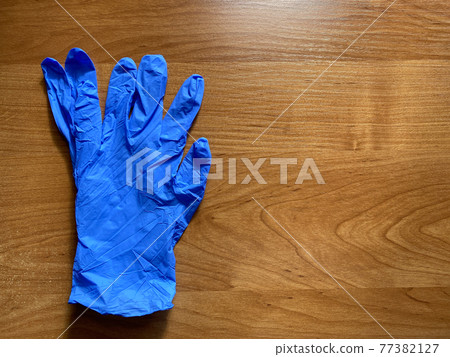 Blue latex gloves on the orange background. Copy space. Sterile protective gloves Blue latex gloves on the orange background. Copy space. Sterile protective gloves 77382127