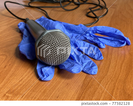 Blue latex gloves and microphone with the cable. The orange background. For the singer. Karaoke, show Blue latex gloves and microphone with the cable. The orange background. For the singer. Karaoke, show 77382128