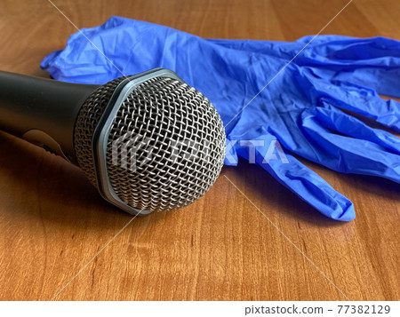 Blue latex gloves and microphone on the orange background. For the singer. Karaoke, show 77382129