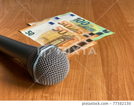 Microphone is next to the money, orange background. Euro banknotes, Pay for karaoke, earn as a singer, buy the microphone Microphone is next to the money, orange background. Euro banknotes, Pay for karaoke, earn as a singer, buy the microphone 77382130