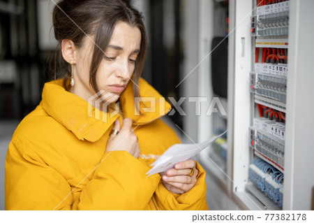 Woman checking bills for electricity at home Woman checking bills for electricity at home 77382178