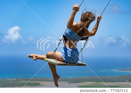 Young beautiful caucasian woman on the rope swing with sea and sky background, view from the Redonda Mountain . Concept of Vacation and travel  77382512