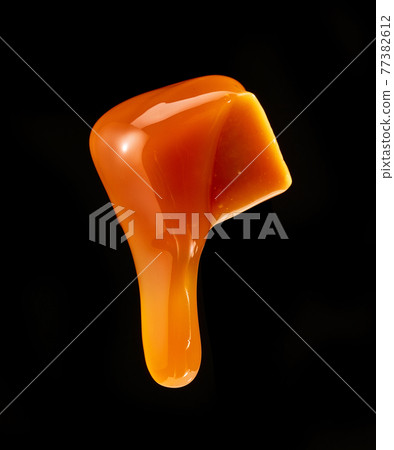 caramel sauce flowing on flying caramel candy 77382612