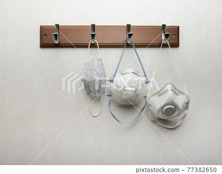 Several respirator masks hanging on clothes rack 77382650