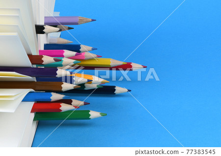 Side view of workplace with pencils between sheets of notebook on blue background. Side view of workplace with pencils between sheets of notebook on blue background. 77383545