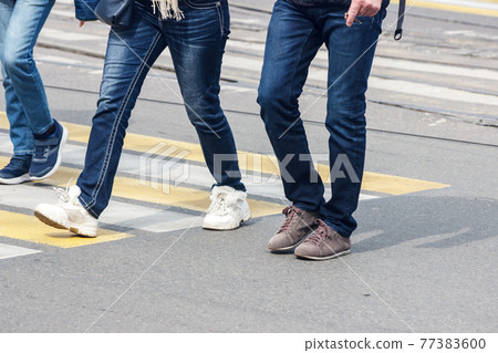 pedestrians cross the street at a pedestrian crossing 77383600