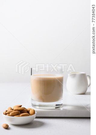 Almond milk in glass bottle and nut. Healthy vegan eating. Almond milk in glass bottle and nut. Healthy vegan eating. 77384043