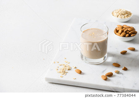 Almond and oatmeal milk in glass on white background. Close up. 77384044