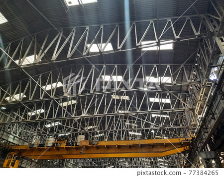 Yellow bridge cranes in a locomotive assembly workshop, the port cranes of ships. Railway cars on loading and unloading. Yellow bridge cranes in a locomotive assembly workshop, the port cranes of ships. Railway cars on loading and unloading. 77384265