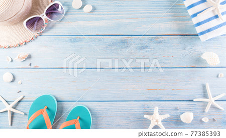 Summer holiday, travel and vacation concept. Sunglasses, starfish, beach hat, flip flop and sea shell on pastel blue wooden background. 77385393