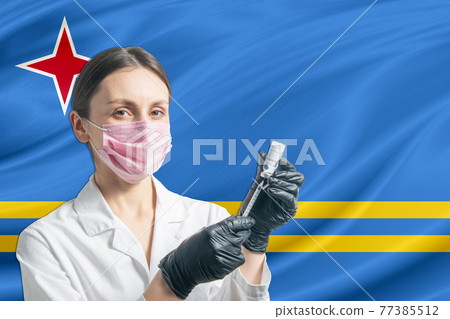 Girl doctor prepares vaccination against the background of the Aruba flag. Vaccination concept Aruba Girl doctor prepares vaccination against the background of the Aruba flag. Vaccination concept Aruba 77385512